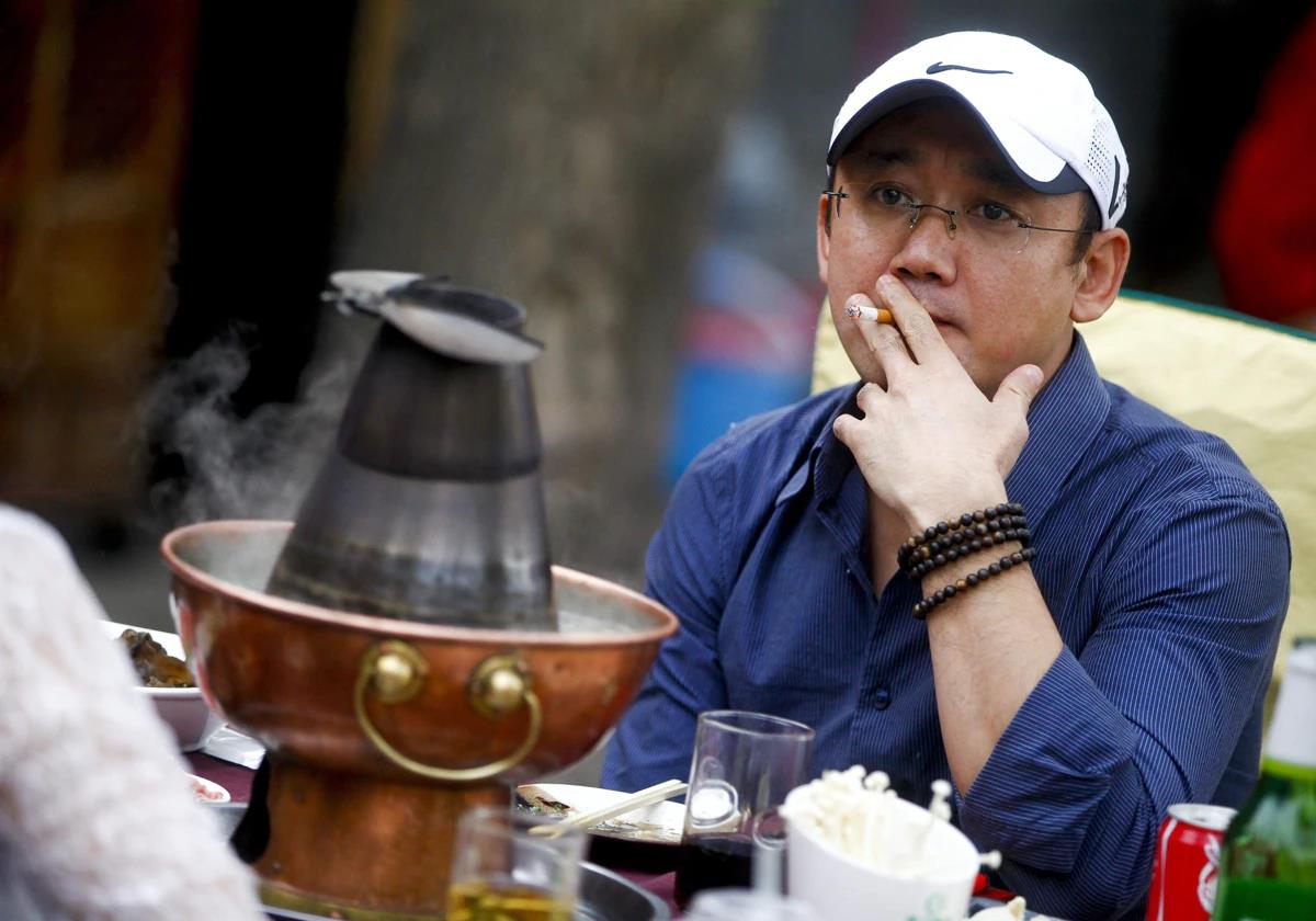 A man smokes a cigarette sitting on the terrace of a restaurant.