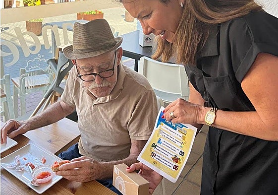 Councillor Lola Ramos hands out a fan and leaflet to a resident.
