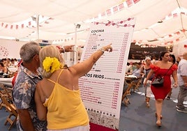 A couple reads the menu prices at a 'caseta' at the city's fairgrounds on Monday.