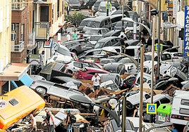 Cars swept along by water piled up in a street in the Valencian municipality of Picaña.