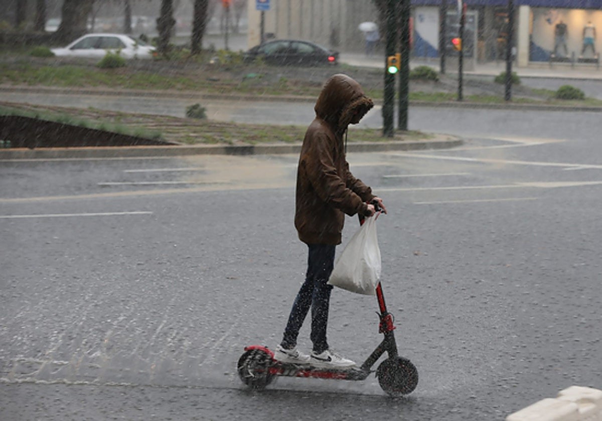 A young person rides a scooter in the rain.