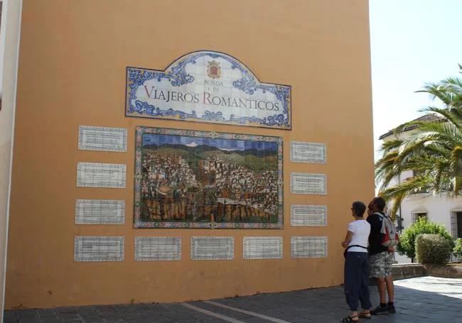 Tourists look at a mosaic depicting romantic travellers in Ronda.