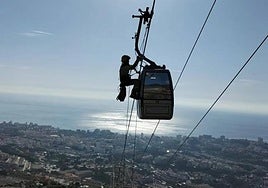 A firefighter slides down one the cables to reach a cable car cabin.