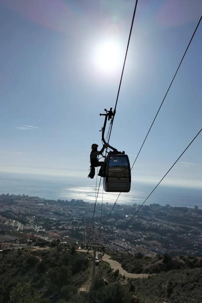 A firefighter slides down one the cables to reach a cable car cabin.