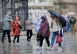 Tourists stroll through the centre of Malaga in the rain today.