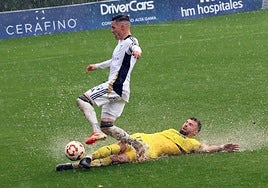 Marbella's José Callejón on the receiving end of a slide tackle in the rain.