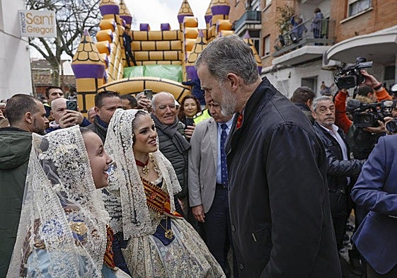 The King of Spain talking to two women in traditional costume.