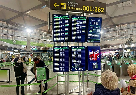 Passengers check their flights at an information panel at Malaga Airport.