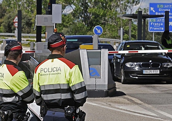 Two Mossos d'Esquadra officers at a toll booth on the AP-7 motorway.