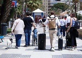 A tourist trundles his suitcases along the seafront promenade of the capital of the Costa del Sol.