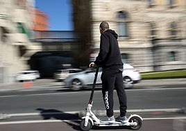 A young man travels around a city on an electric scooter.