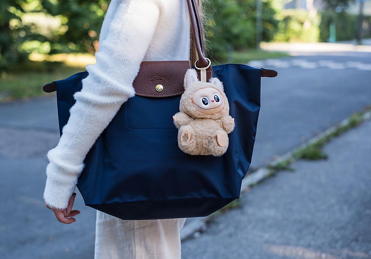 Teenage girl with her Longchamp bag attached to a Labubu keychain.