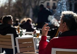 A man smokes a cigarette on the terrace of a bar in Madrid.