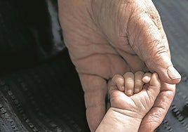 A grandfather holds his grandson's hand.