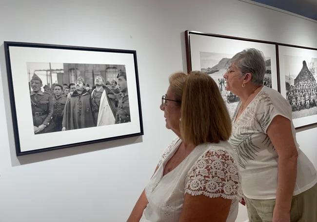 Two visitors look at the famous photograph Bartolomé Ros took of Franco and Millán Astray, embracing while they sang legionary songs, at the exhibition inaugurated in Alhaurín de la Torre.