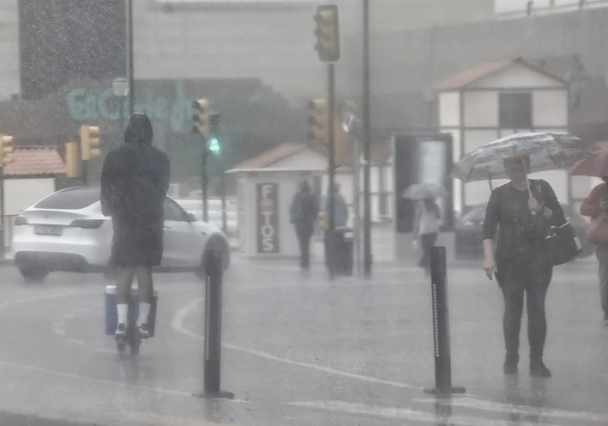 Man rides a scooter in the area around El Corte Inglés in Malaga city during the rain.