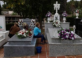 Two women keep vigil by their loved ones' graves at Malaga's San Gabriel cemetery.