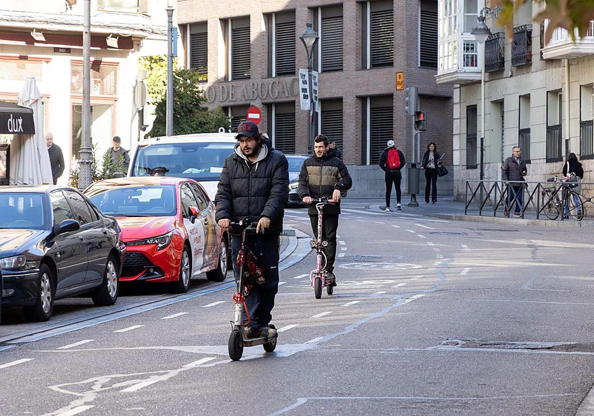 Two electric scooter riders make their way through Valladolid city centre.