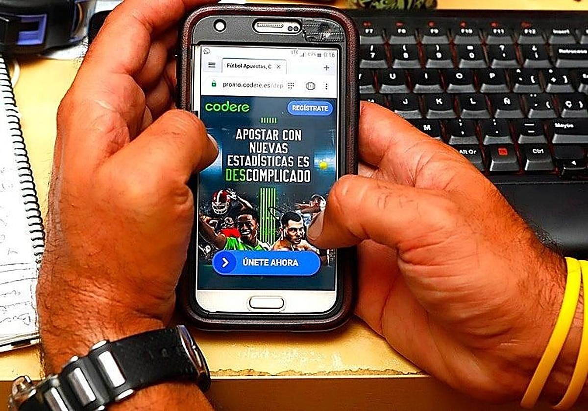 A man uses his mobile phone to access the website of an online bookmaker.