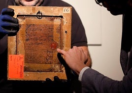 The curator points to the wax seal of the British monarchy on the back of the oil painting of Philip II.