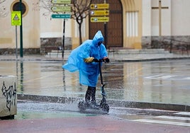A person rides an electric scooter in the rain in Malaga.