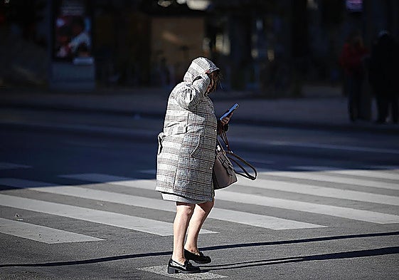 A woman shields herself against the cold weather in Malaga with thick coat.