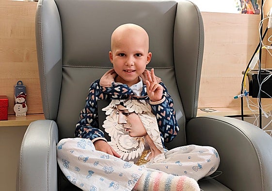 The little girl poses for a photo at the Virgen del Rocío hospital, with a picture of the Virgin of Hope in her hands.