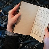A person wearing tartan reads a book of poems by Robert Burns .