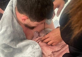 The father holding his baby in his arms, seconds after his partner gave birth in the street in Mijas.