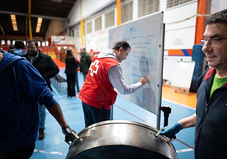 Volunteers walk past the blackboard where the lunch and dinner menus are written down each day.