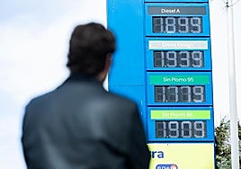 A driver checking fuel prices at a low-cost petrol station in Spain.