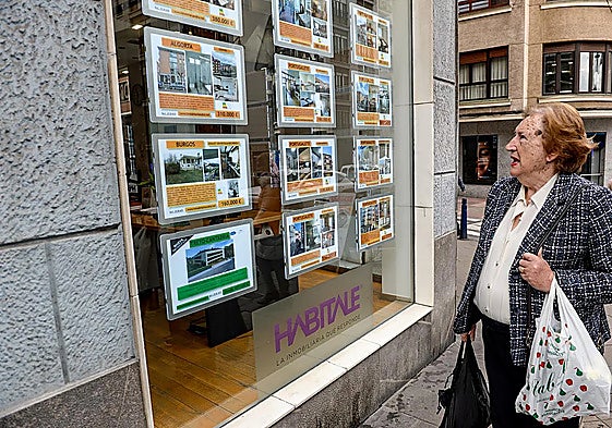 A woman looking at the ads on a real estate agency's display.