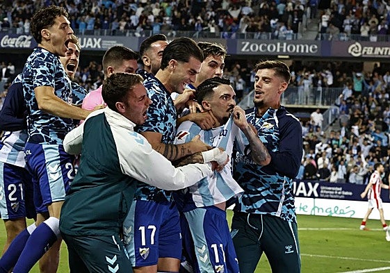 The Malaga players join goalscorer Joaquín in celebrating the vital goal.