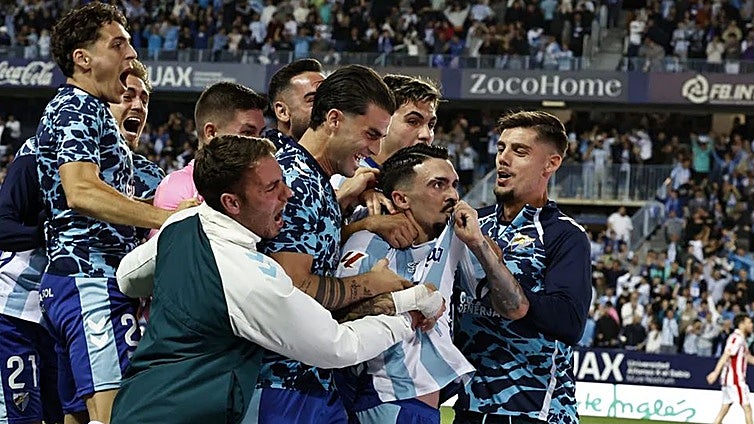 The Malaga players join goalscorer Joaquín in celebrating the vital goal.