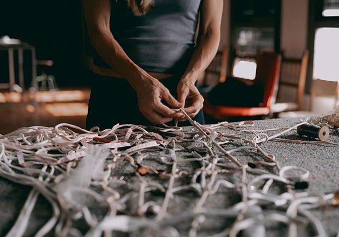 Julia Llerena weaves a net using bedroom items given to her by locals.