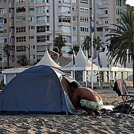 A man entering his tent at the La Malagueta beach in Malaga.