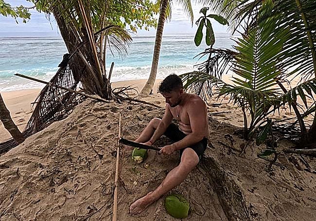 Adrián cuts open a coconut to eat.