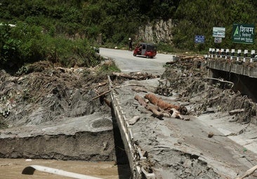 An auto rickshaw drives past a broken bridge following a flash flood in Galchhi/The torrent of water, about to flood a building.