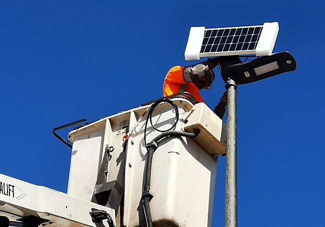 A workman is installing a solar-powered street lamp.