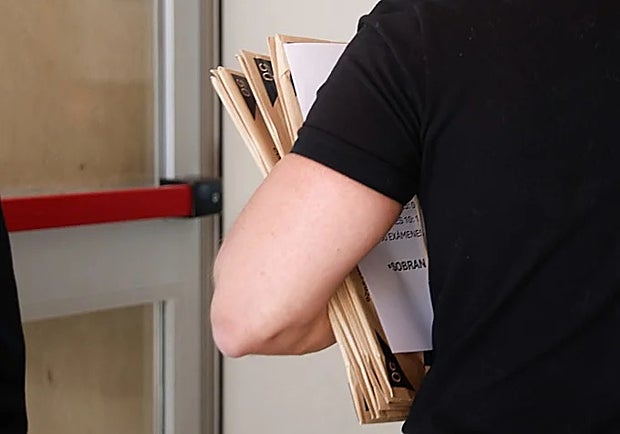 A teacher carrying some exam papers.