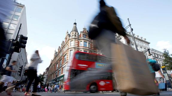 A shopper crosses Oxford Street, the commercial heart of London.