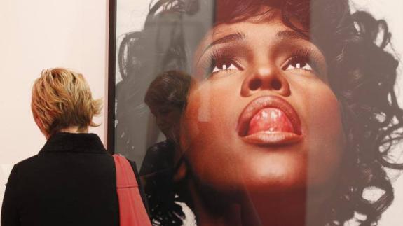 A visitor studies a portrait of Whitney Houston by Michel Comte.