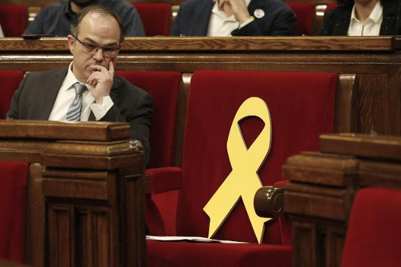 Turull next to the empty seat of Puigdemont in the parliament.