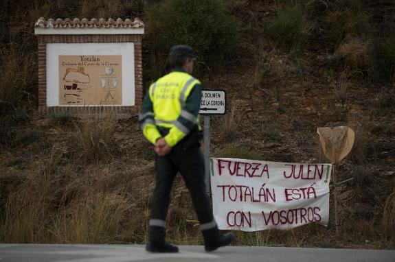 A Guardia Civil officer walks past a sign put up by locals.