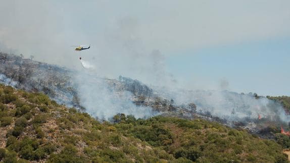 A helicopter douses the flames from above.