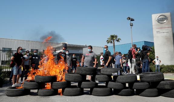 Workers set tyres alight at the factory gate after the news broke.