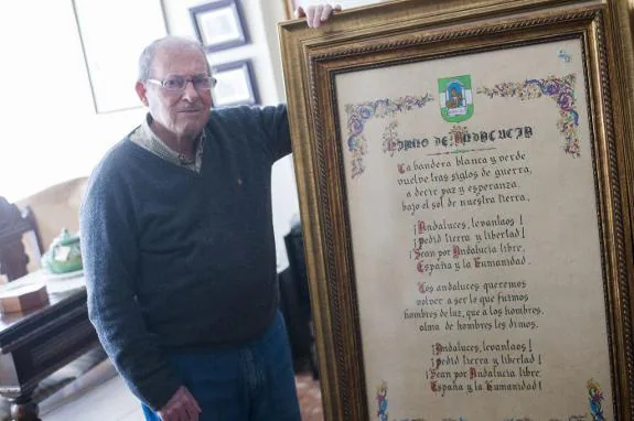 An artist with the framed words of the Andalusian anthem.