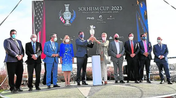 Juan Marín and Marta Figueras-Dotti lift the Solheim Cup next to Francisco Salado and representatives of other institutions. 