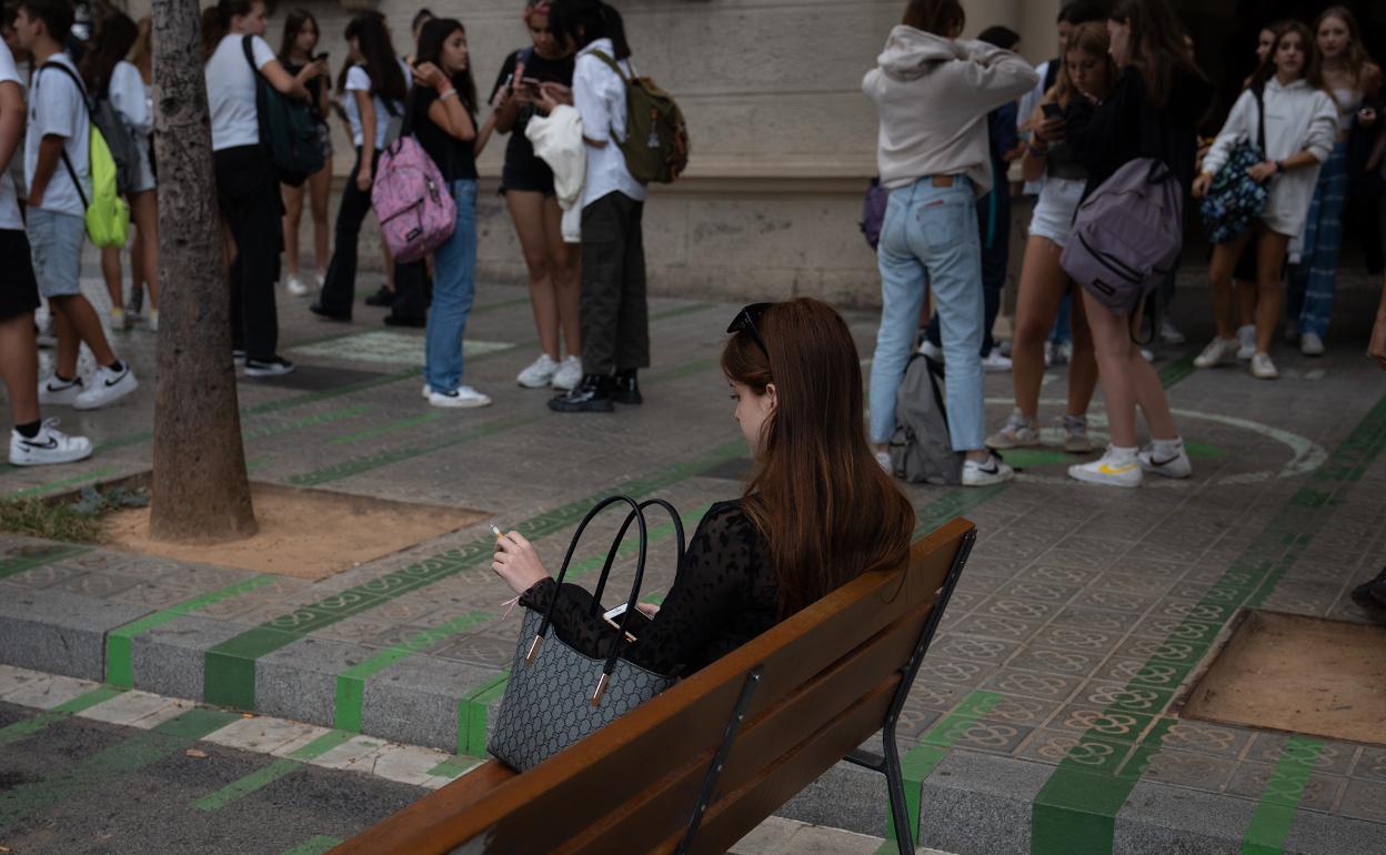 Una mujer fumando ante un grupo de adolescentes. 