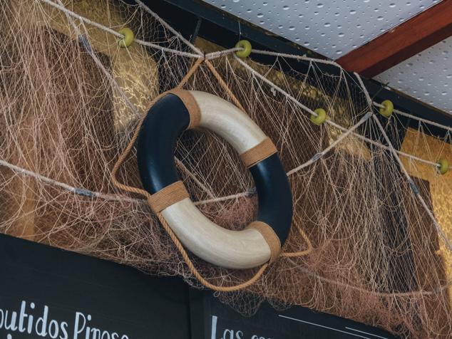 Redes pescadoras y un flotador adornan lo alto de la barra